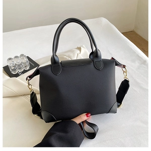Detail of black nylon tote bag with leather trim and gold metal hardware hooks