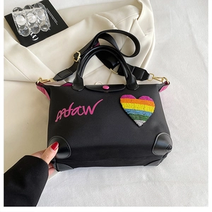 Detail of black nylon tote with rainbow heart patch and pink embroidery accent