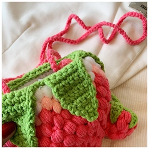 Detail of pink handmade crochet strawberry bag with green leaf accents and fine texture
