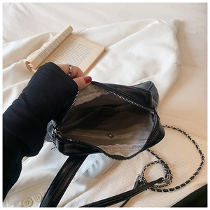 Detail of black glossy crossbody bag showing interior lining and zipper pocket