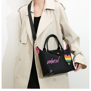 Detail of black canvas tote with pink leather accents and sparkling rainbow heart patch