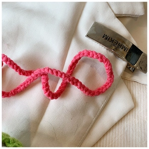 Detail of silver engraved metal hair clip and magenta braided crochet rope accessory