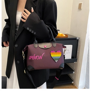 Detail of burgundy nylon handbag with rainbow heart sequin and leather handles