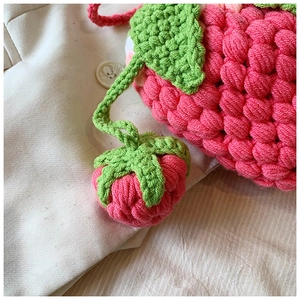 Detailed view of handmade crochet strawberry bag featuring pink bubble stitch and green leaves