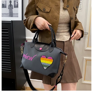 Detail of grey nylon handbag showing leather flap with pink button and heart patch