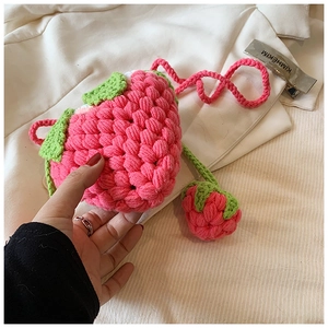 Detailed view of handmade strawberry crochet bag with pink yarn and green leaf decor