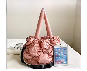 Comparaison de taille d'un sac cabas rose matelassé à côté d'une tablette montrant sa capacité