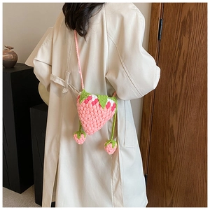 Detailed view of hand-knitted pink strawberry crossbody bag with green leaf accents