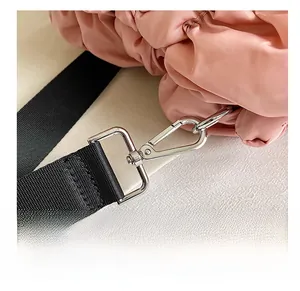 Détail d'un sac en nylon rose matelassé avec sangle noire et crochet en métal argenté