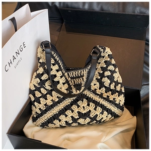 Detail of hand-woven geometric straw tote bag presented in an elegant black gift box