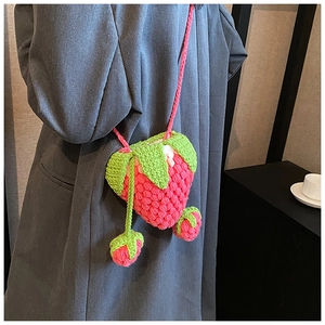 Detail of a handmade pink crochet strawberry crossbody bag with green leaf accents