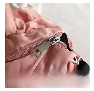 Détail de la fermeture éclair argentée sur un sac à bandoulière en nylon matelassé rose