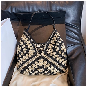 Detail of the black and beige woven hobo bag with intricate crochet pattern and leather strap