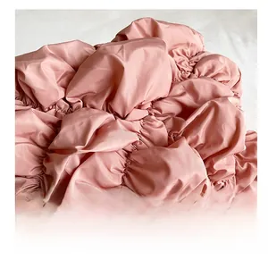 Détail macro du tissu matelassé rose avec fini satiné et texture plissée élégante