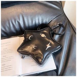 Macro shot of star-shaped black faux leather bag with silver celestial metal charms