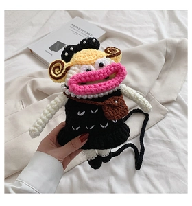 Detailed view of handmade crochet crossbody bag with funny face and pearl necklace