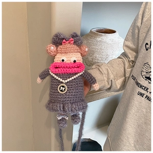 Vue détaillée d'un pendentif poupée au crochet gris avec de grands yeux et lèvres