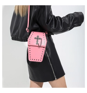 Vue détaillée d'un sac à bandoulière rose en forme de cercueil avec clous et croix
