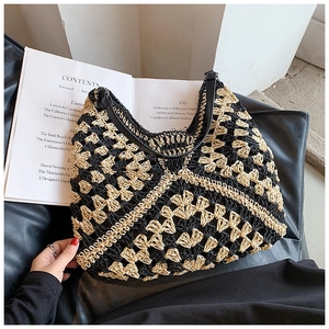 Detailed close-up of geometric pattern on woven straw hobo bag with black leather strap