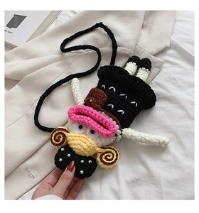 Macro detail of hand-knitted cartoon bag featuring pearl beads and soft cotton texture