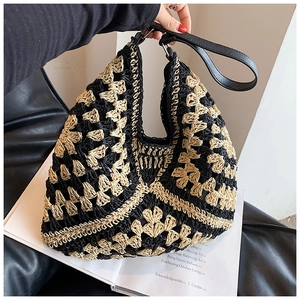 Detail of the woven geometric floral pattern and black leather strap on the straw bag