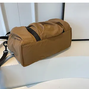 Detailed bottom view of large khaki nylon travel bag with black strap and buckle