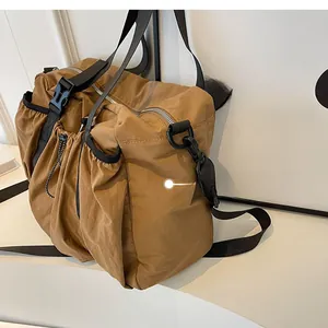 Close-up of caramel nylon tote bag featuring drawstring side pocket and durable buckle detail