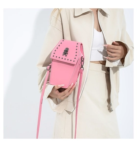 Détail du sac bandoulière gothique rose avec rivets noirs et emblème de crâne en métal