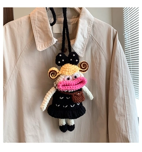Detail of a handmade crochet doll pendant with pearls on a beige trench coat