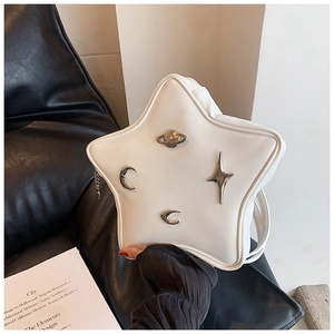 Detail of white star-shaped bag with silver celestial charms on a black leather background