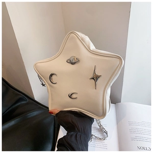 Detail of star-shaped crossbody bag with metallic moon and planet badges and chain strap