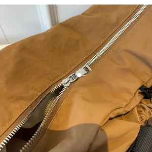 Detail of smooth silver metal zipper and brown nylon fabric on functional travel bag