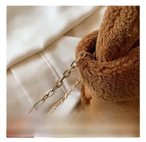 Detail of golden metal chain strap and soft brown faux fur texture on a bucket bag