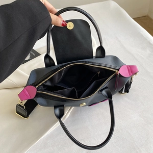 Black nylon tote bag with leather trim and pink side detail, interior view with pockets