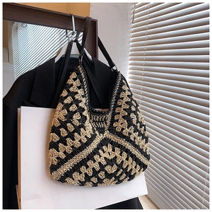 Detail of hand-woven straw hobo bag featuring contrast floral texture and leather strap