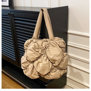 Vue détaillée du sac cabas beige matelassé à texture froncée suspendu à un meuble noir