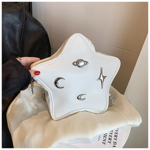 Detail of star-shaped white leather bag with metallic planet and moon ornaments