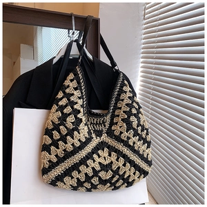 Detailed texture of geometric crochet weave on a black and beige hobo shoulder bag