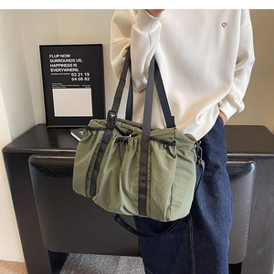 Olive green nylon tote bag featuring ruching detail and black webbing shoulder straps