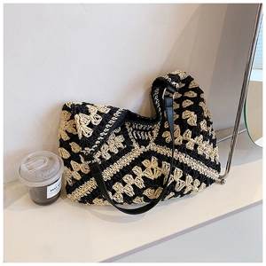 Close-up of bohemian woven straw tote bag with geometric pattern and black leather strap