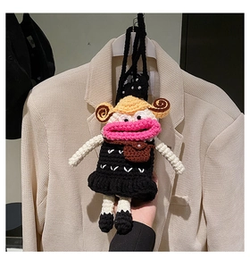 Detail of handmade crochet cartoon character bag with pink lips and black shoulder strap