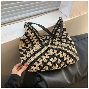 Detail of crochet tote bag featuring black and beige geometric pattern and leather strap