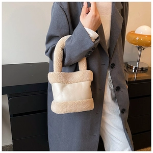 Chic beige plush fleece and leather bucket bag detail on stylish model suit