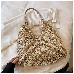 Detail of hand-woven straw tote with hollow fan pattern and brown leather handle
