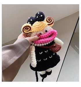 Detailed view of handmade crochet doll charm with pearl necklace and black dress