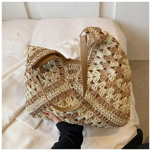 Close-up of dual-tone straw hobo bag with hollow crochet patterns and leather strap