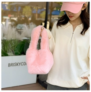 Detailed view of pink plush handbag with a fluffy faux fur texture and wide handle