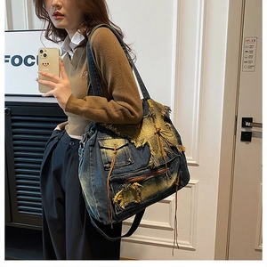 Vintage-Denim-Tote-Tasche mit Distressed-Fransen und Patchwork-Details an der Schulter getragen