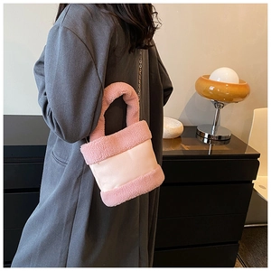 Detailed close-up of pink plush patchwork bucket bag with metal chain strap on a model