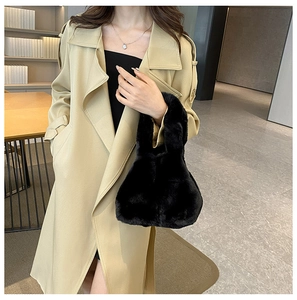 Detail of a black plush faux fur handbag styled with a khaki trench coat for autumn